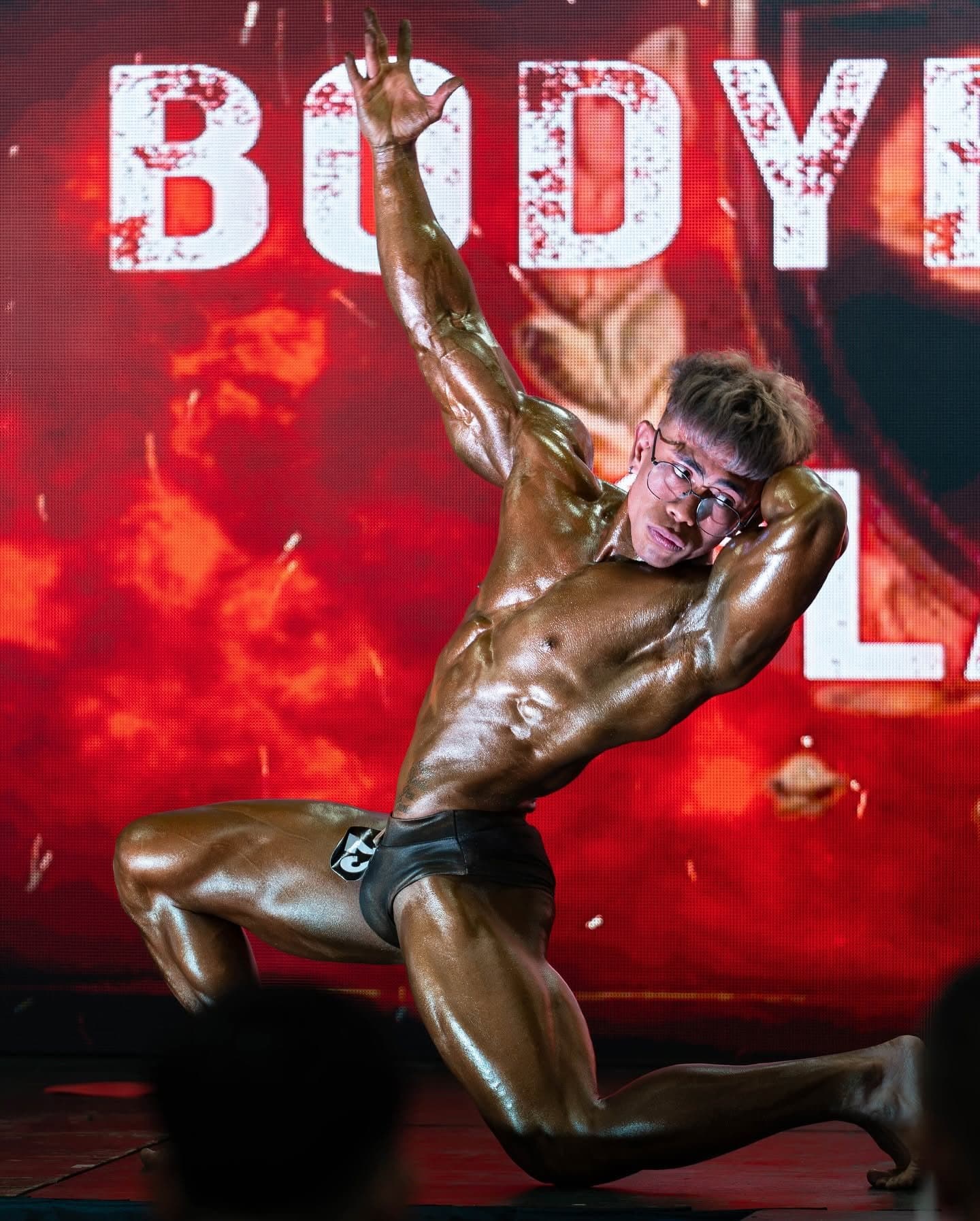 Coach Jaycob holding a kneeling pose on a red-lit stage
